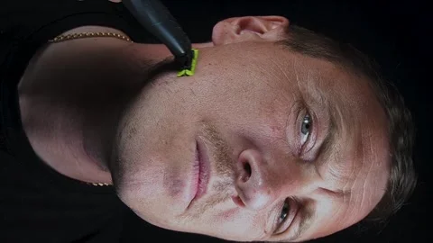 Young man shaving his face with a trimmer Stock Footage 308538124