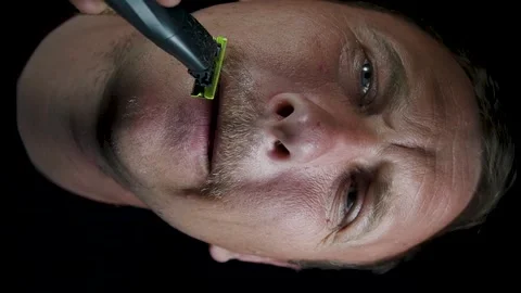 Young man shaving his face with a trimmer Stock Footage 308538125