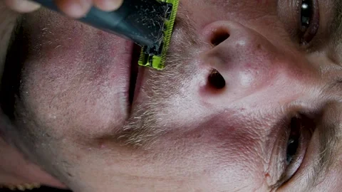 Young man shaving his face with a trimmer Stock Footage 308538133