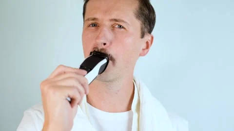 Young man  shaving his mustache with modern electric razor 스톡 동영상 165383003