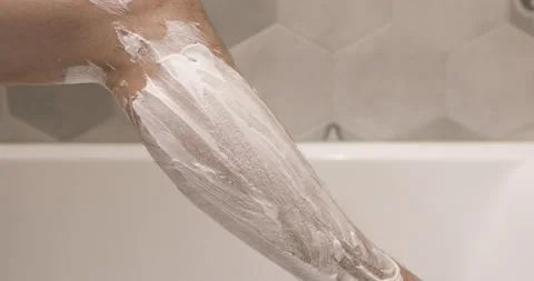 Young man is shaving leg using disposable razor in bathroom, leg closeup. Stock Footage 137438937
