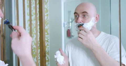 Young man is shaving using disposable razor in bathroom, closeup, side view Stock Footage 171110597