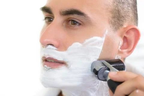Young man shaving using electric shaver Stock Photos
