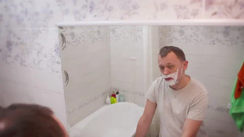 Young  man shaving while standing in the bathroom in front of the mirror Stock Footage 140270898