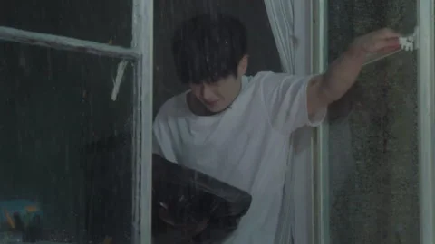 Young man sheltering a small black dog from heavy rain Video stock 333804339
