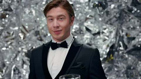 Young Man On Shiny Background With Glasses Of Champagne. Party. He Raises His Stock Footage 179065242
