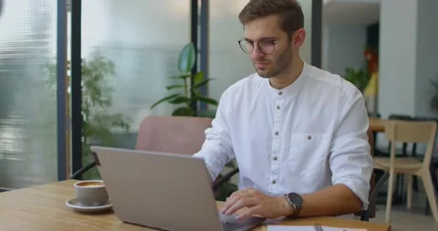 Young man in shirt sitting in cafe,working online,scrolling websites and Stock Footage 160920239