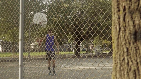 Young man shooting hoops at an outdoor basketball court. Slider shot. Stock Footage 80344151