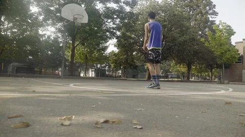 Young man shooting hoops at an outdoor basketball court. Stock Footage 80352004