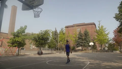 Young man shooting hoops at an outdoor basketball court. Stock Footage 80355405