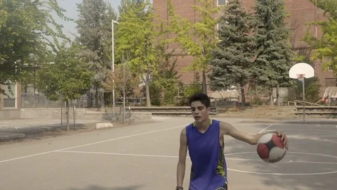Young man shooting hoops at an outdoor basketball court. Stock Footage 80356590