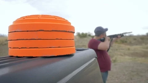 Young Man Shoots Target Practice at the Gun Range With Orange Clay Pigeons Stock Footage 88596117