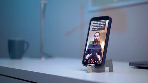 A young man shoots a video on a smartphone while reading text from a Stock Footage 259308733