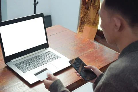 Young man shopping online in e commerce, holding credit card and smartphone with Foto stock
