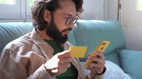 Young man shopping online using mobile cell phone and credit bank card on the 스톡 동영상 231144038