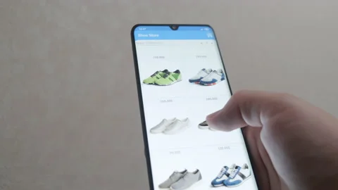 A young man is shopping through a mobile app. Buys shoes online. Online shopping Video stock 132210699