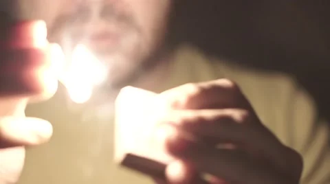 Young man with a short beard burning a match in the dark Stock Footage 56958107