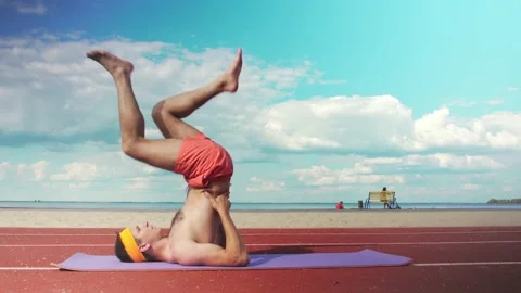 A young man in shorts without a T-shirt is doing fitness on the playground.  Stock Footage 199252749