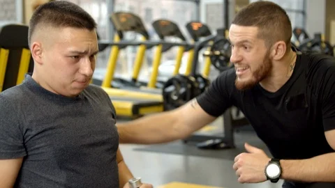 Young man shouted at by instructor while working out in gym Stock Footage 125532864