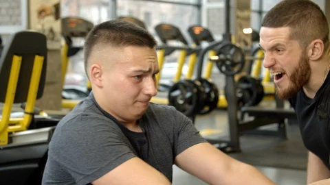 Young man shouted at by instructor while working out in gym Stock Footage 125533328