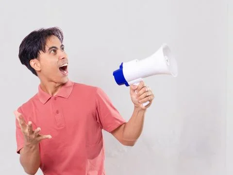 Young man shouting through a megaphone with one hand outstretched while sho.. Stock Photos