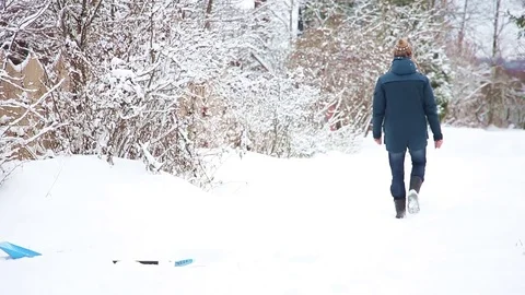 Young man with the shovel clears snow, then drops shovel and goes away Stockbeeldmateriaal 83780959