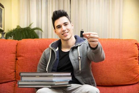  Young man showing difference between USB drive and heavy books Smiling yo... Stock Photos