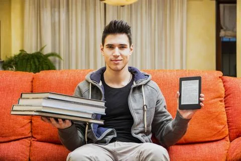  Young man showing difference between ebook reader and heavy books Smiling... Stock Photos