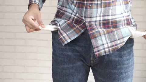 Young man showing empty pockets inside out while standing against white bri.. Stock Footage 332747249