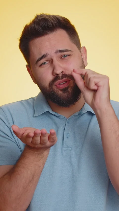 Young man showing a little bit gesture with sceptic smile showing minimum sign Stock Footage 333460141