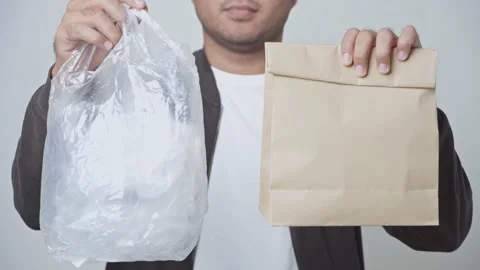 Young man showing of plastic bag and paper bag. He argued to reduce the use of p Stock Footage 145177272