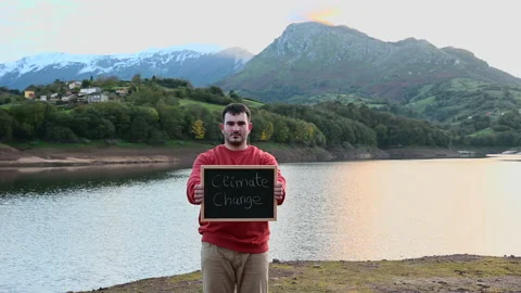 A young man showing a sign protesting against climate change in nature Stock Footage 164774208