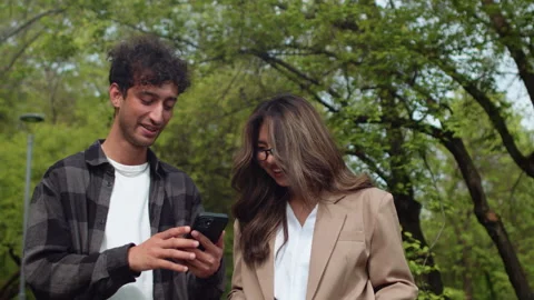 Young man showing something on a smartphone to a young woman, and then they Stock Footage 276543515