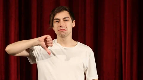 Young man showing thumb down on red curtain background Stock Footage 112215905