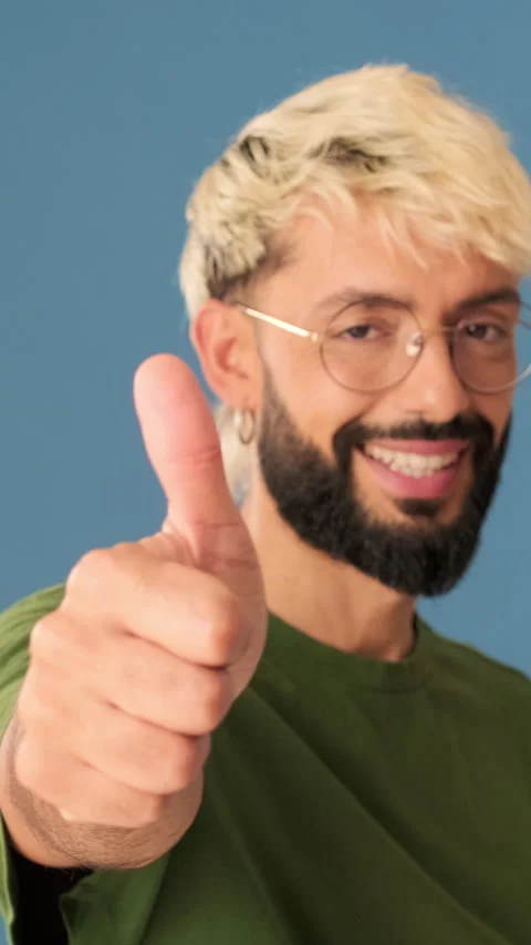 Young man showing thumb up gesture, isolated on blue background in studio Stock Footage 308813692