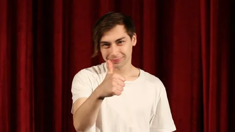 Young man showing thumb up on red curtain background Stock Footage 112215811