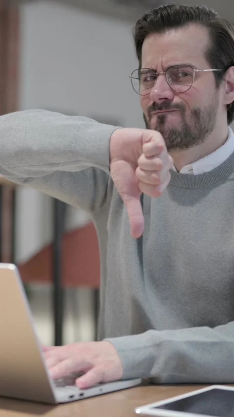Young Man Showing Thumbs Down Sign While using Laptop at Work, Vertical Video Stock Footage 339580740