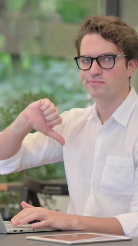 Young Man Showing Thumbs Down Sign While Using Laptop at Work, Vertical Video Stock Footage 340032201