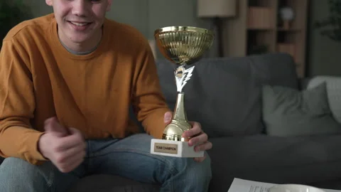 Young man showing off trophy during video call Stock Footage 328361112