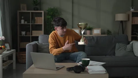 Young man showing off trophy during video call Stock Footage 328361183