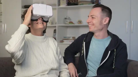 Young man showing virtual reality glasses to an old woman. Elderly woman smiling Video stock 68645342