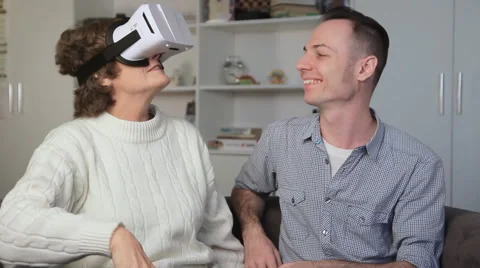 Young man showing virtual reality glasses to an old woman. Elderly woman smiling Video stock 68645424
