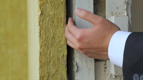 Young man shows and explains the thermal insulation of the wall Stock Footage 161999332