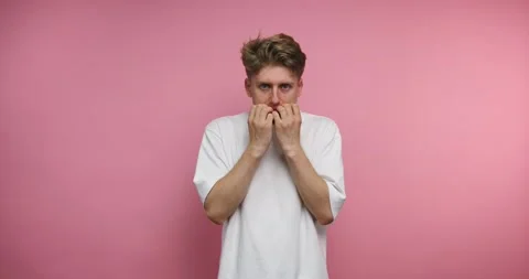 Young man shows different emotions in front of a pink wall while covering h.. Stock Footage 317327901