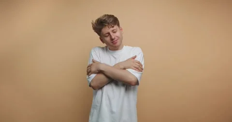 Young man shows different expressions while embracing himself against a pla.. Vídeo Stock 328247091