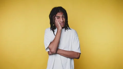 Young man shows different expressions in front of yellow background while p.. Vídeos de archivo 328249715