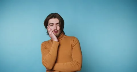 Young man shows different expressions against a blue background in simple p.. Vídeo Stock 328249939
