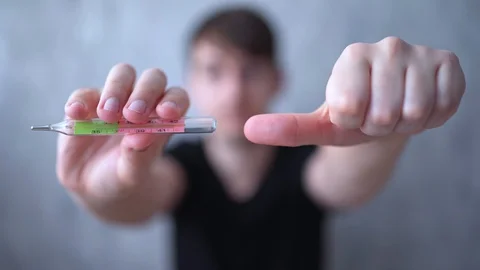 A young man shows a high temperature on medical thermometer and dislike Stock Footage 127030507