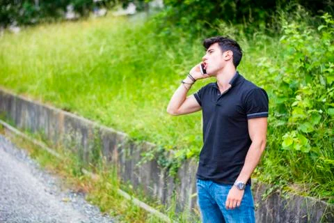 Young man on side of a road, calling and waiting for taxi Stock Photos