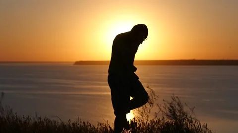 Young man silhouette against bright golden sunset gladness lucky success Stock Footage 50962953